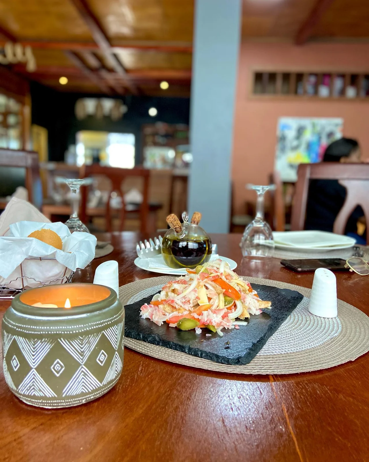 Une table dressée chez Koll, une bougie et une entrée fraîche sur ardoise