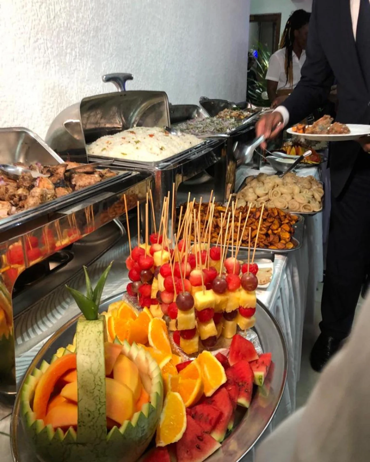 Un buffet traiteur avec brochettes de fruits, grillades et miondo