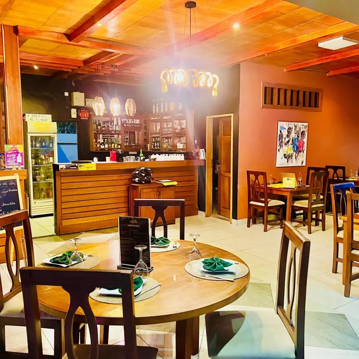 La salle chaleureuse de Chez Koll, ses tables rondes, son plafond en bois et ses luminaires tressés